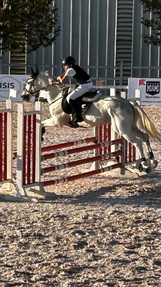 Aluno saltando obstáculo durante prova de hipismo
